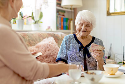 Betreuerin spielt mit älterer Frau ein Kartenspiel